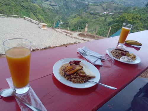 un tavolo con un piatto di cibo e un bicchiere di succo d'arancia di Glamping La Mardo a Cartago