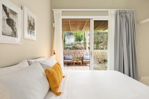 a bedroom with a white bed and a patio at The OliveStone Village - Yoga Retreat Paradise in Ágios Márkos
