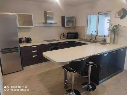 une cuisine avec un grand comptoir blanc et des appareils électroménagers dans l'établissement Appart T3 avec jardin proche commerces et aéroport, à Borgo