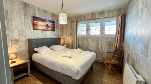 1 dormitorio con 1 cama, 1 silla y 1 ventana en Appt avec vue EXCEPTIONNELLE sur la baie + garage, en Le Crotoy