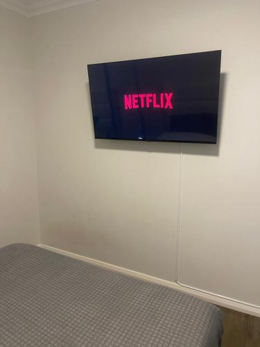 un televisor en una pared con el cartel de netflix en él en Modern room in Perth city !!, en Perth