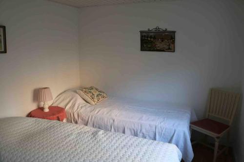 a bedroom with two beds and a lamp on a table at Ängelsbäcksstugan in Båstad