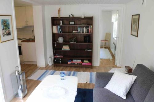 a living room with a couch and a book shelf at Ängelsbäcksstugan in Båstad
