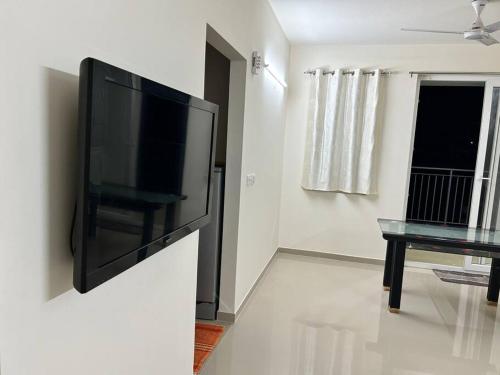 a flat screen tv hanging on a wall in a living room at San Service Apartment by Dolfy in Kelambākkam
