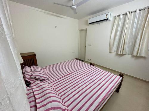 a bedroom with a striped bed and a window at San Service Apartment by Dolfy in Kelambākkam