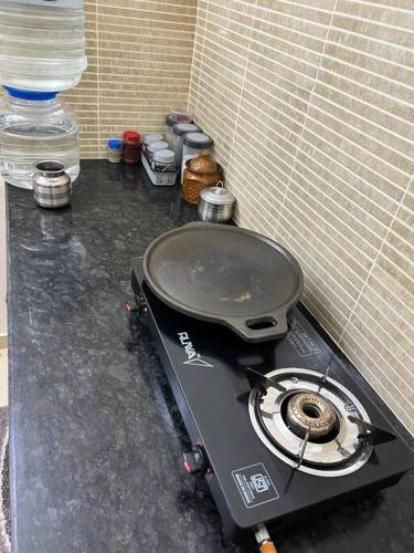 a stove top with a pot on top of a counter at San Service Apartment by Dolfy in Kelambākkam