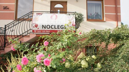 a sign on the side of a building with flowers at Noclegi Pod Różą in Krasnobród