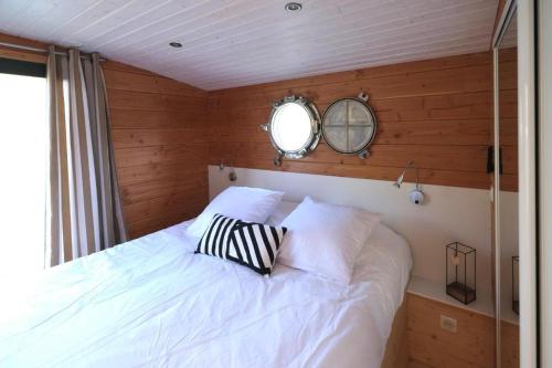 a bedroom with a white bed with a mirror on the wall at Les Cabanes de Lara in Ménesplet