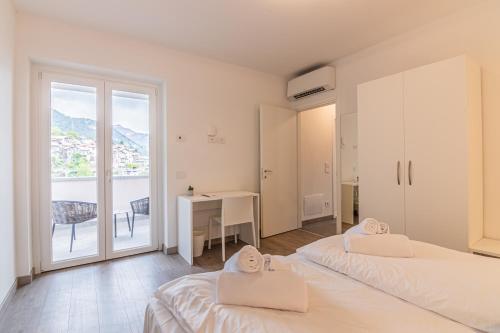 a bedroom with two beds and a desk and a window at VILLA DEI VENTI NORTH by Curtiaffitti in Pianello Del Lario