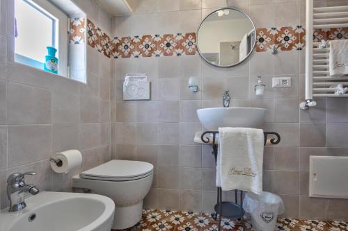 a bathroom with a toilet and a sink and a mirror at Borgo Diaz in Cisternino