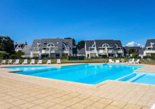 une grande piscine avec des chaises et des maisons en arrière-plan dans l'établissement Appartement avec piscine proche thalasso et plages, à Carnac