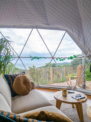 un salon avec une grande fenêtre en verre dans l'établissement Domaine de Sonia - Logements éco-insolites, à Porto-Vecchio