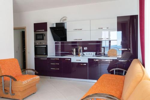 a kitchen with purple cabinets and an orange chair at BluApartments 3,Shëngjin Seaview in Shëngjin