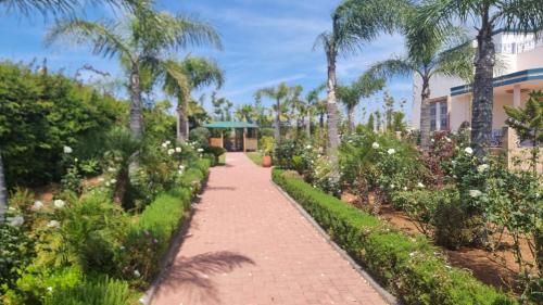 un sentiero attraverso un giardino con palme e un edificio di Ferme d'hôtes de luxe a Skhirat