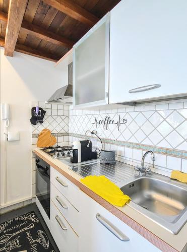 uma cozinha com armários brancos e um lavatório em Colibrì em Nettuno