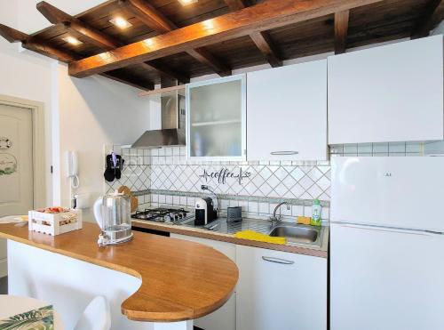 Il comprend une cuisine équipée d'un réfrigérateur blanc et d'une table en bois. dans l'établissement Colibrì, à Nettuno