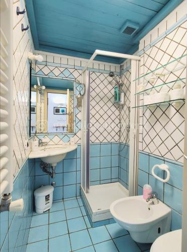 La salle de bains bleue est pourvue d'un lavabo et d'une douche. dans l'établissement Colibrì, à Nettuno