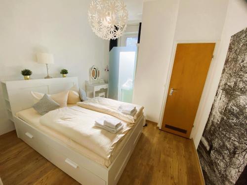 a bedroom with a bed with white sheets and a chandelier at Peters Aparthotel in Goslar