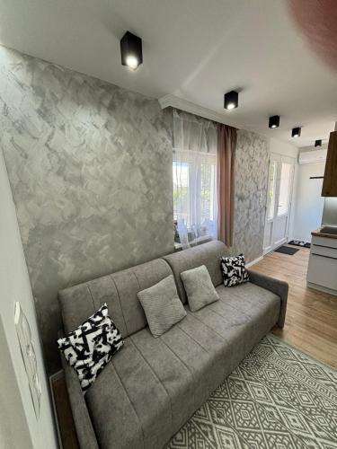 a living room with a couch and a stone wall at Belvárosi Lux Apartman 2 in Vásárosnamény
