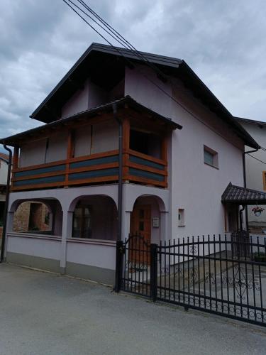 a white house with a black fence in front of it at Apartman EMA in Kulen Vakuf