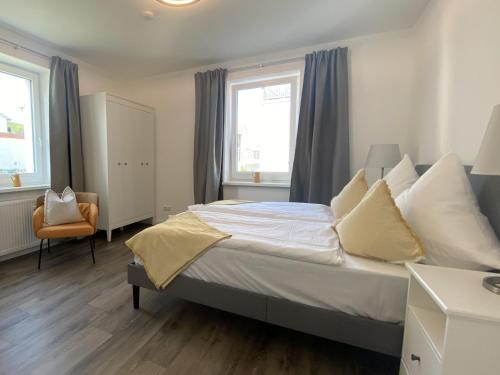 a bedroom with a large bed and two windows at Villa Rosalie Sassnitz in Sassnitz