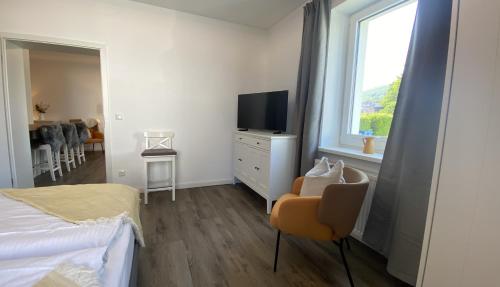 a bedroom with a bed and a television and a chair at Villa Rosalie Sassnitz in Sassnitz