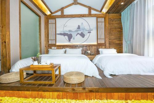 a bedroom with two beds and a table at Pure House in Zhangjiajie