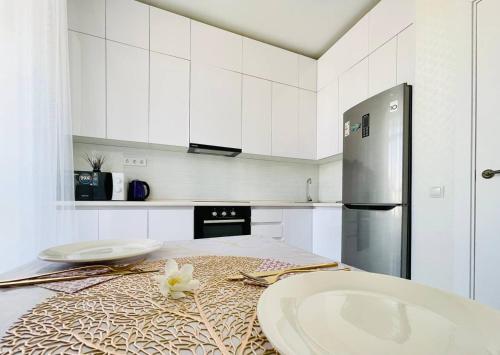 a kitchen with white cabinets and a counter with a sink at Manhattan 5 Astana city in Taldykolʼ
