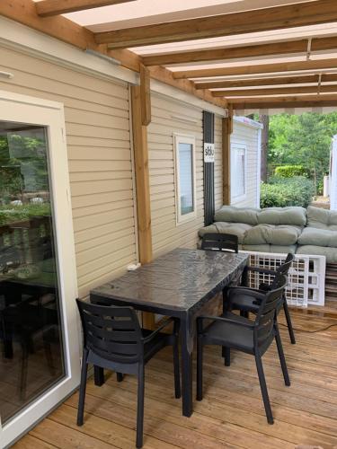 une table noire et des chaises sur une terrasse dans l'établissement MH 008 Bora Bora sur emplacement exceptionnel en lisière de forêt dans camping 4 étoiles, à Saint-Julien-en-Born