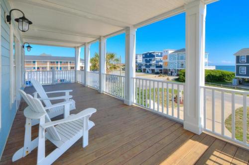 a porch with white chairs and a view of the ocean at Starboard Side in Oak Island