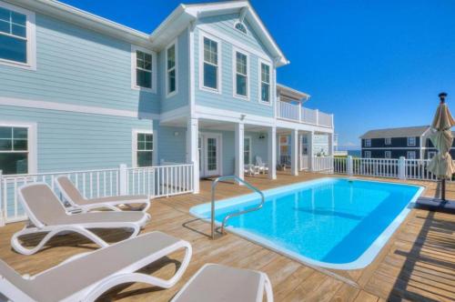a house with a swimming pool in front of a house at Starboard Side in Oak Island