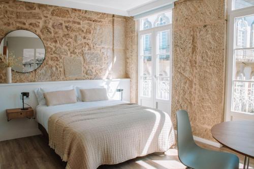 a bedroom with a bed and a table and chairs at Just Like Home - Vilavelha Suites in Valença