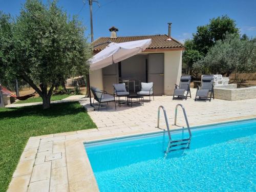 una piscina con sillas, una sombrilla y una casa en Accogliente villa con piscina en Caltagirone