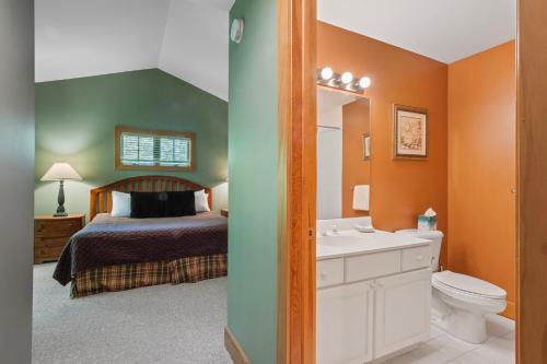 een slaapkamer met een bed en een badkamer met een wastafel bij 666 Disciples Village Condo in Boyne Falls