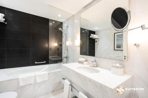 a white bathroom with a sink and a mirror at Fashion avenue Dubai Mall -The Residence in Dubai