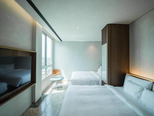 a hotel room with two beds and a tv at PAPO'A Harbor Hotel in Kaohsiung