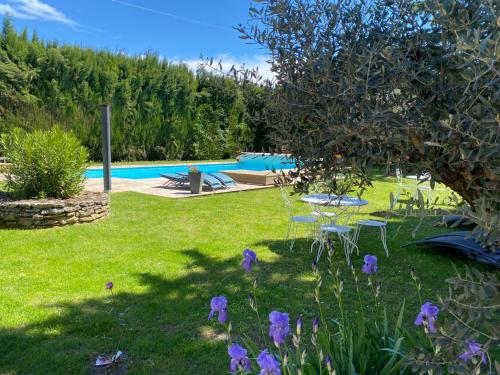 einen Hof mit lila Blumen und einem Pool in der Unterkunft Studio avec terrasse privative et piscine in Grillon