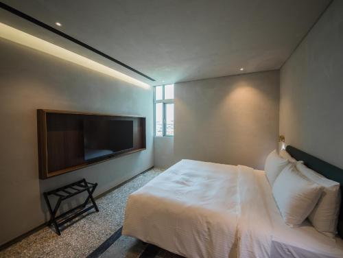 a bedroom with a white bed and a flat screen tv at PAPO'A Harbor Hotel in Kaohsiung