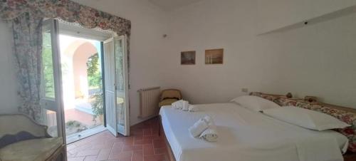 a white room with a bed and a large window at Villa Francesca - Camere con giardino in Castellaneta