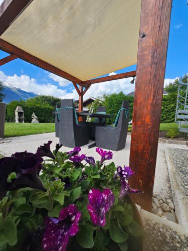 a table and chairs under a gazebo with purple flowers at Chez Gigi in Apro