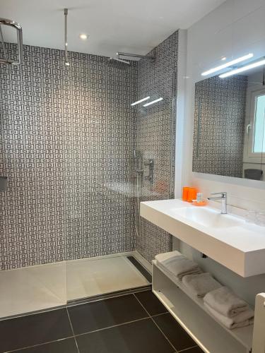 uma casa de banho com um lavatório e um chuveiro em Hôtel Valencia em Hendaye