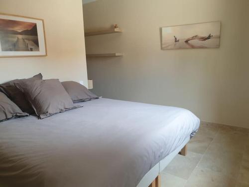 - un lit blanc dans une chambre avec 2 photos sur le mur dans l'établissement Location indépendante au cœur des Alpilles pour 2 personnes avec Jacuzzi, à Aureille