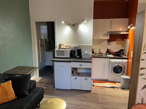 a small kitchen with a microwave and a stove at Studio Cosy en cœur de ville in Pau