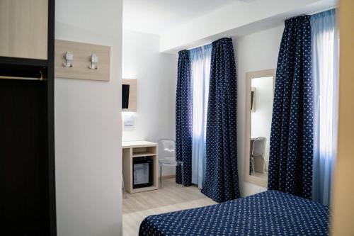 Habitación con cortinas azules, cama y espejo. en Alloggi Pontecorvo Liviana en Padova