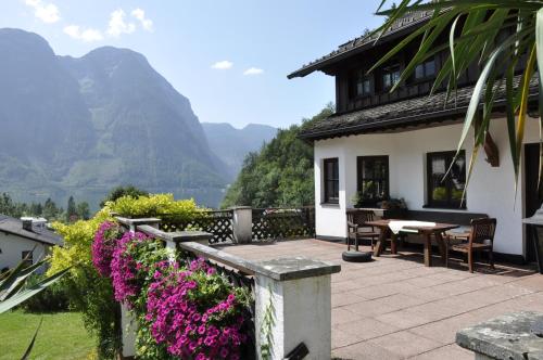 a house with a patio with a table and flowers at Apartment Stadler in Obertraun