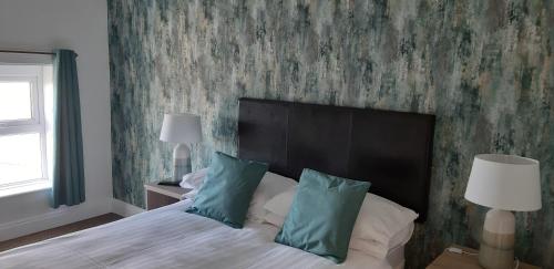een slaapkamer met een groot bed met groen behang bij The Astor in Ballybunion