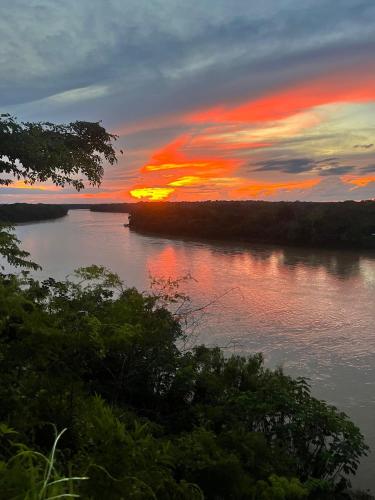 a sunset over a body of water with trees at Sunrise of Tambopata in Puerto Maldonado
