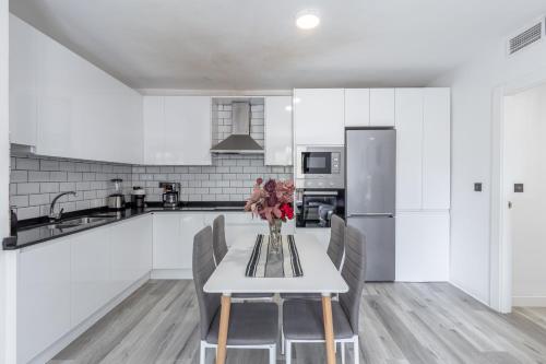 a white kitchen with a table and chairs at Dreaming Ogíjares in Ogíjares
