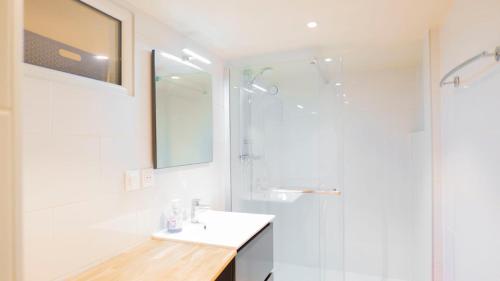 a white bathroom with a sink and a shower at studio jardin à st Denis in Saint-Denis