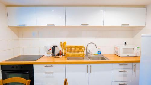 une cuisine avec des armoires blanches et un évier dans l'établissement studio jardin à st Denis, à Saint-Denis